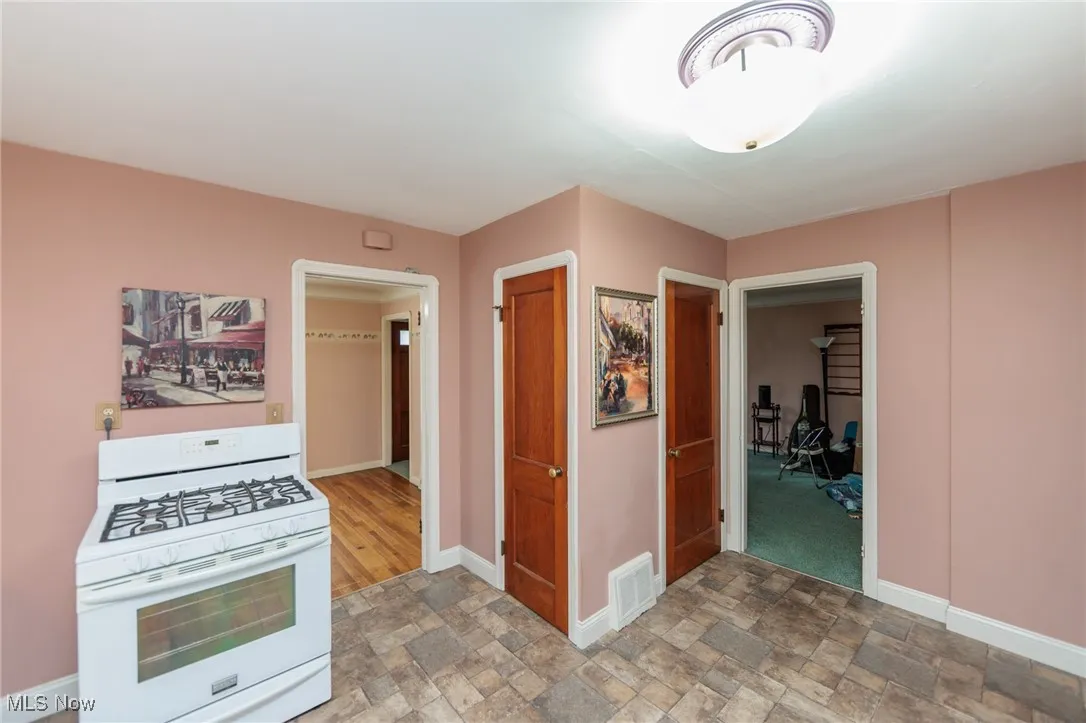 Kitchen featuring white gas range oven and stone finish floors