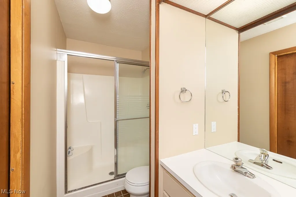 Bathroom featuring vanity, a stall shower, a textured ceiling, and tile patterned floors