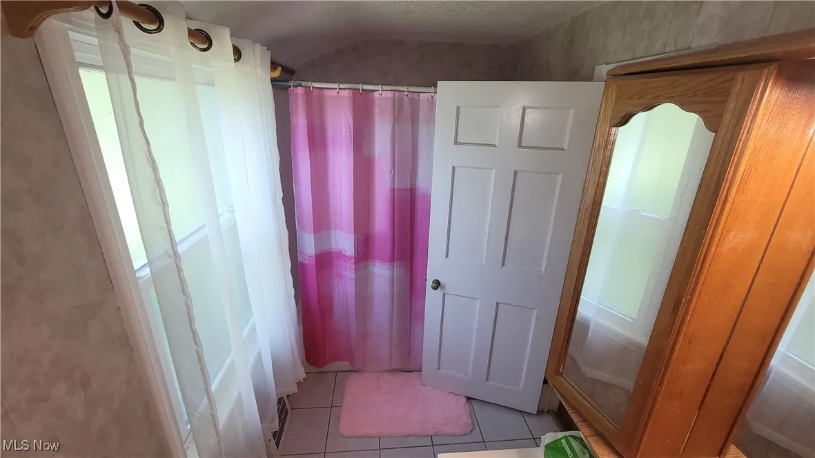 Bathroom with light tile patterned floors and a shower with curtain