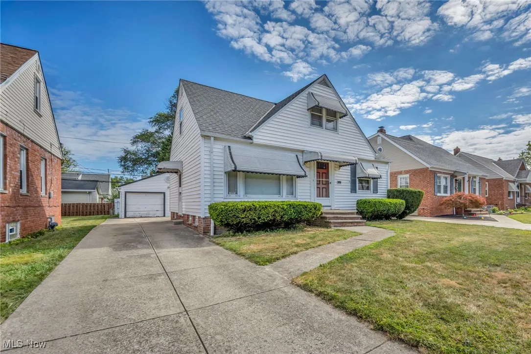 Bungalow-style house with a shingled roof, an outdoor structure, and a detached garage