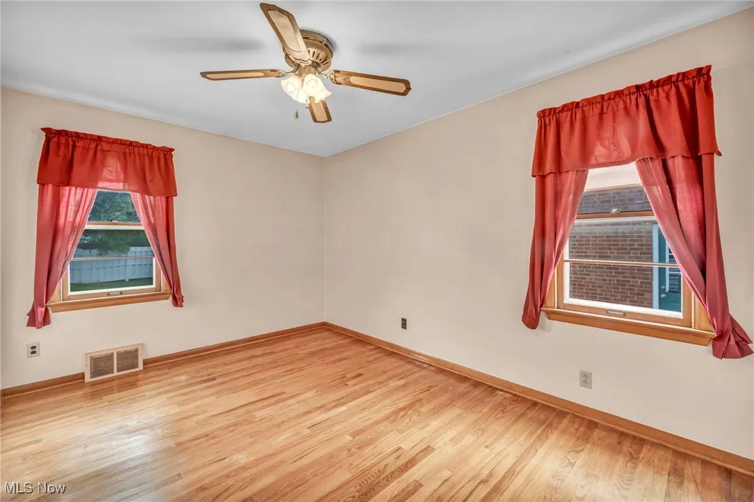 Empty room featuring light wood-type flooring and a ceiling fan