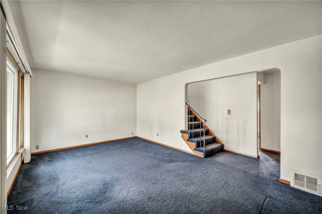 Empty room featuring carpet, a textured ceiling, and stairway