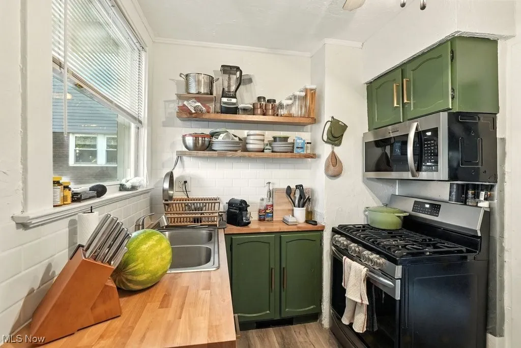 Kitchen featuring green cabinets, butcher block countertops, stainless steel appliances, dark wood-style flooring, and open​​‌​​​​‌​​‌‌​‌‌​​​‌‌​‌​‌​‌​​​‌​​ shelves