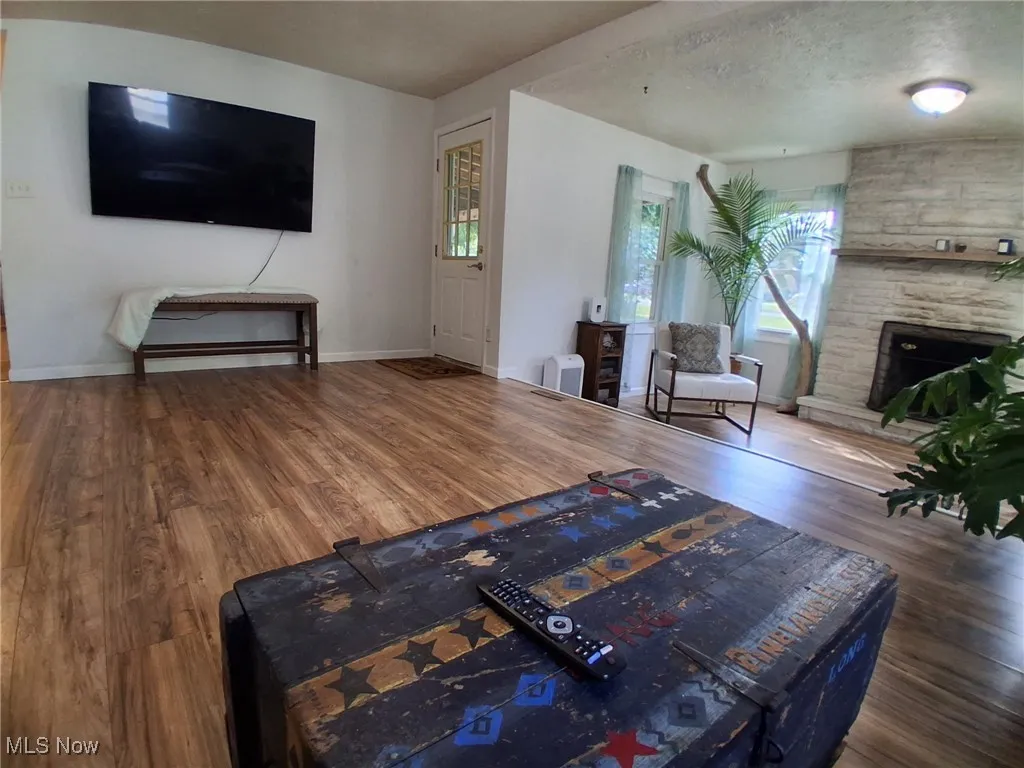 Living area with dark wood-type flooring, a fireplace, healthy amount of natural light, and a textured ceiling