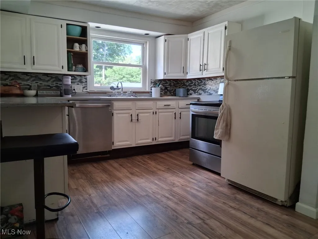 Kitchen featuring white cabinets, stainless steel appliances, and dark wood finished floors