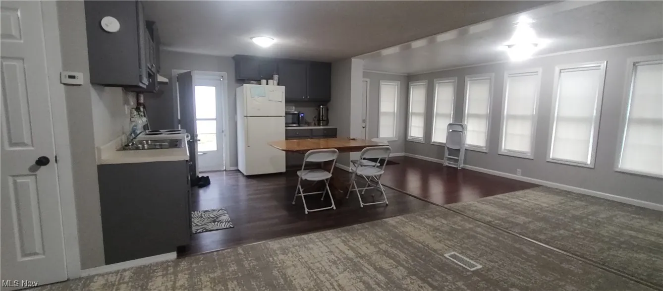 Kitchen with freestanding refrigerator, a breakfast bar, dark wood finished floors, wood counters, and a center island