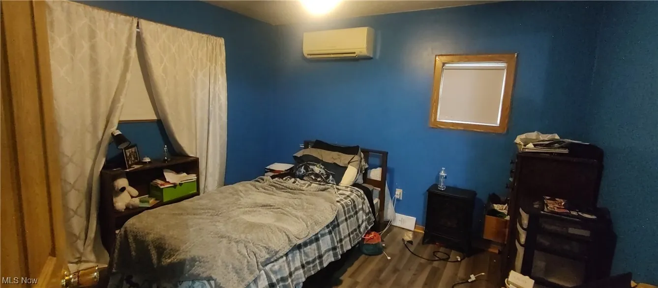 Bedroom featuring wood finished floors and a wall mounted air conditioner