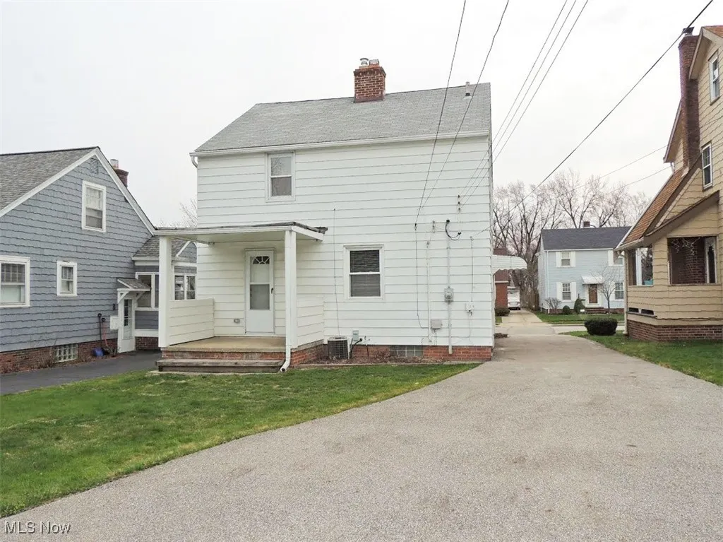 Rear view of house with a chimney, a lawn, and a porch