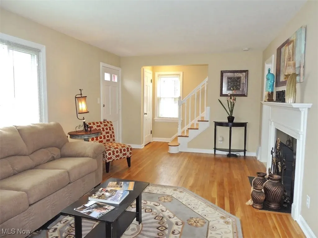 Living room featuring wood finished floors, stairway, and a fireplace