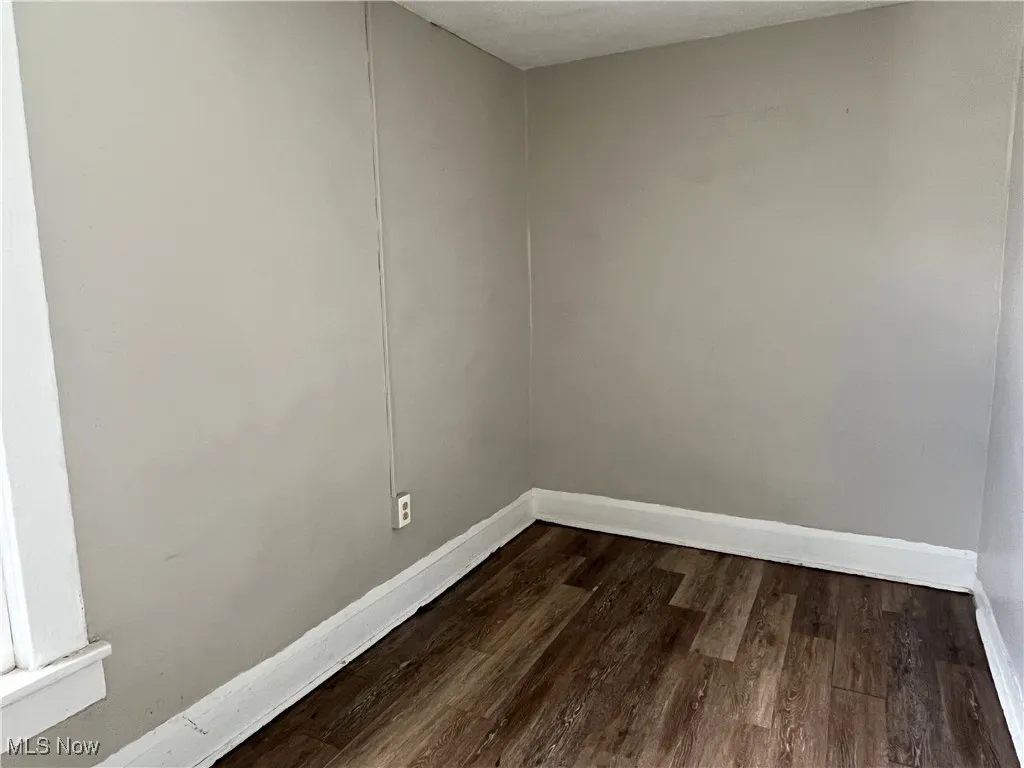 Unfurnished room with dark wood-style flooring