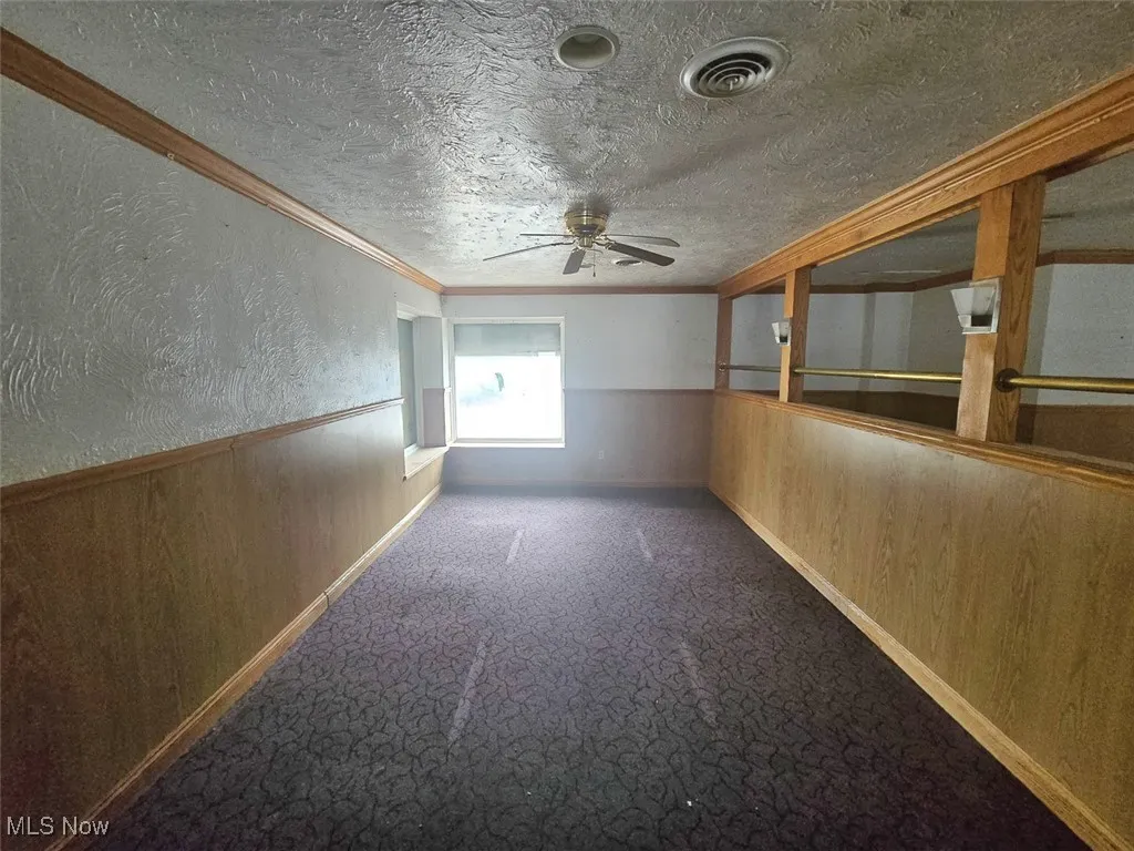Additional living space with wood walls, wainscoting, carpet floors, a textured wall, and a textured ceiling