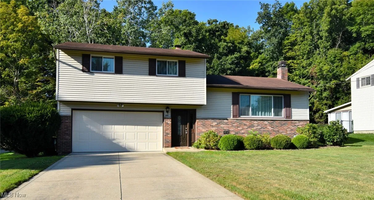 Tri-level home with a chimney, brick siding, concrete driveway, and an attached garage