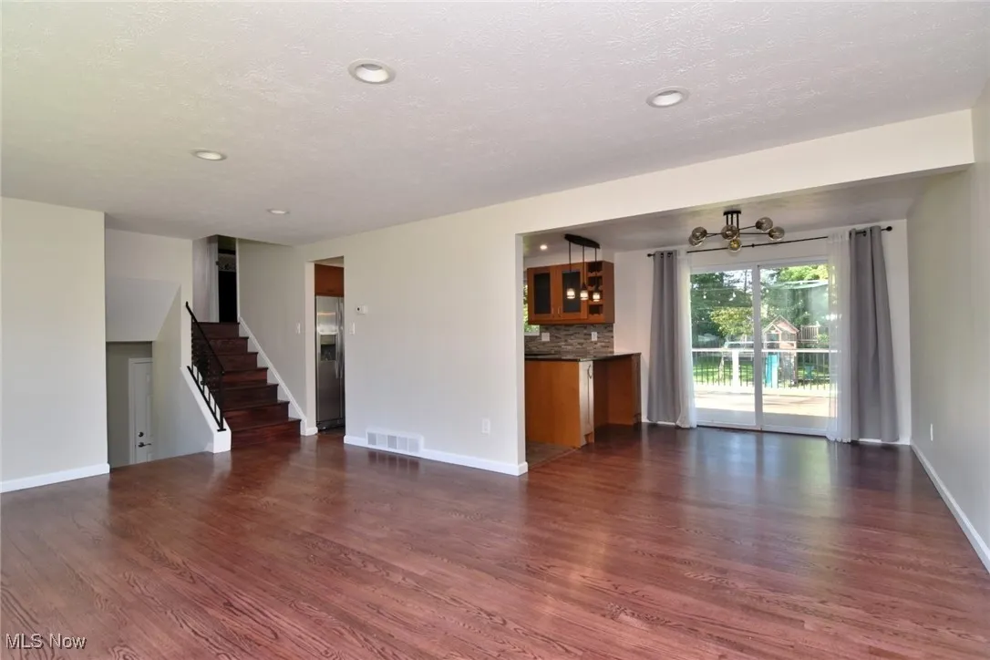 Unfurnished living room featuring dark wood finished floors, stairway, recessed lighting, and a textured ceiling