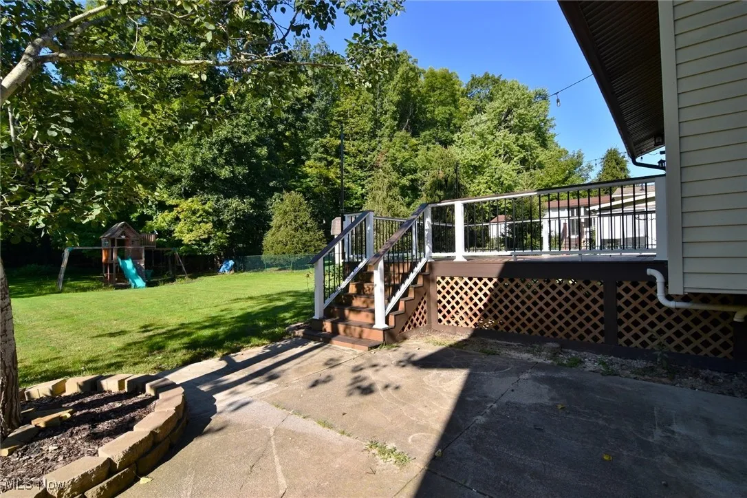 View of patio featuring a playground, a wooden deck, and stairway