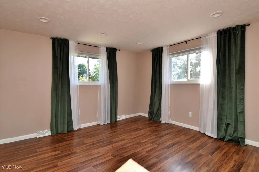Unfurnished room with dark wood finished floors and a textured ceiling