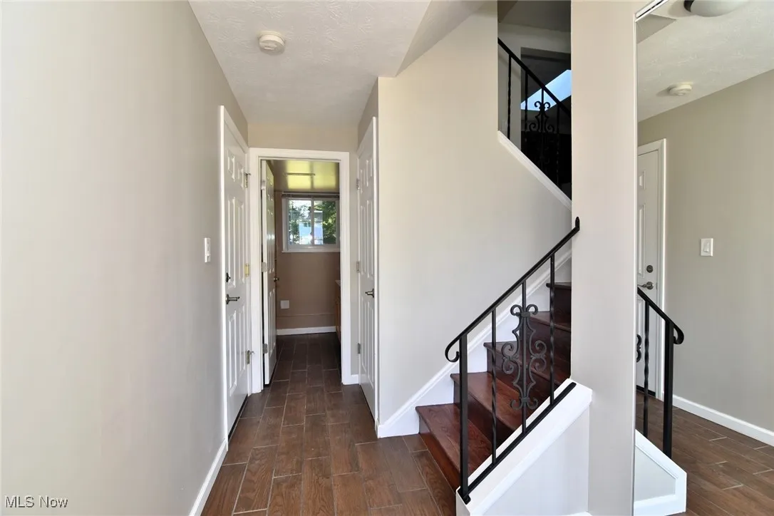 Stairs with wood finished floors and a textured ceiling
