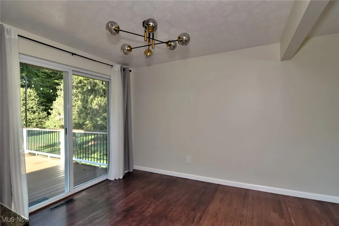 Unfurnished dining area with dark wood finished floors, a textured ceiling, and a chandelier