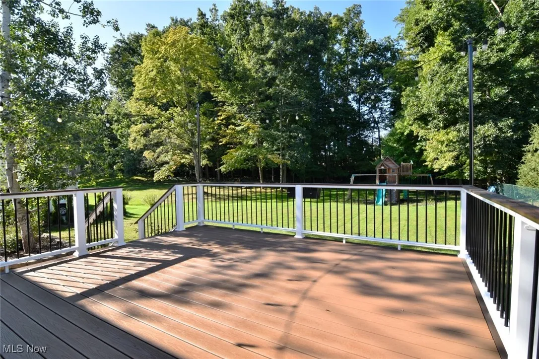 Wooden deck featuring a playground and a yard