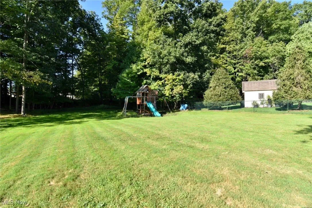 View of yard with a playground and view of scattered trees