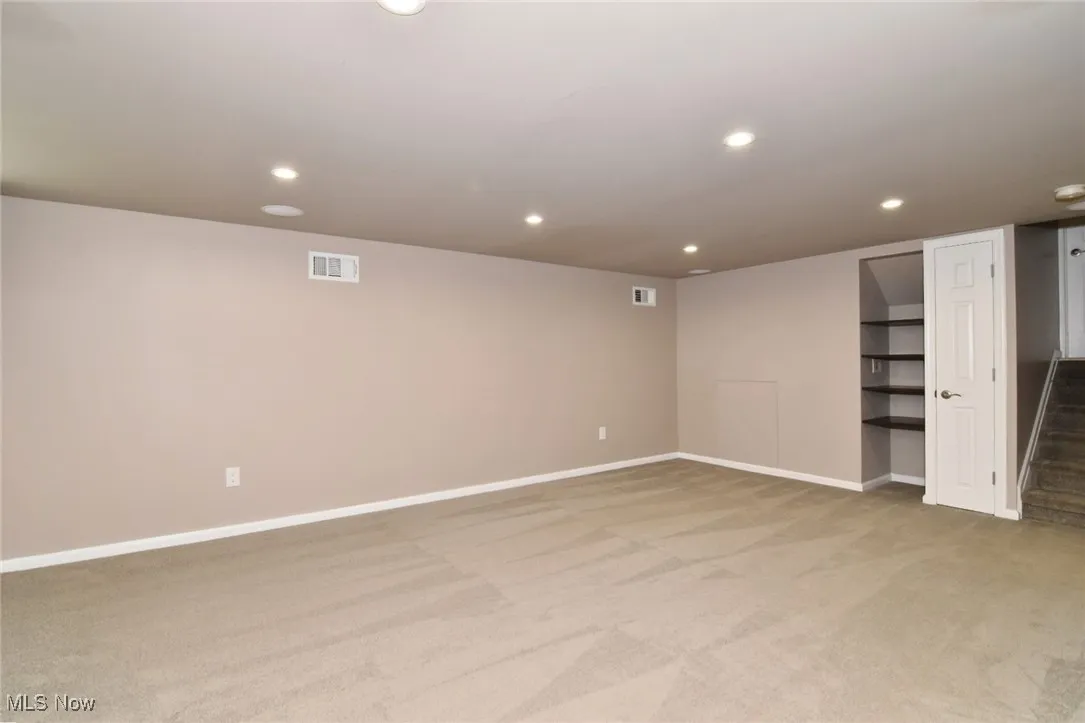 Finished below grade area featuring recessed lighting, light carpet, and stairway