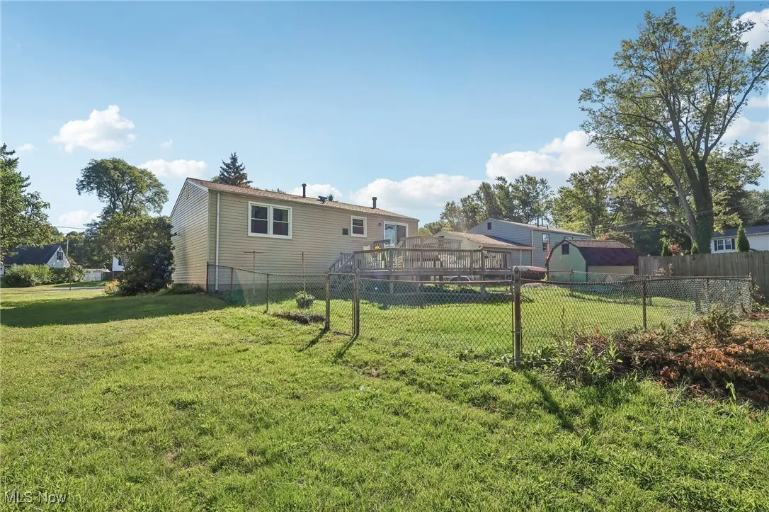 Rear view of property featuring a deck, a fenced backyard, and an outbuilding