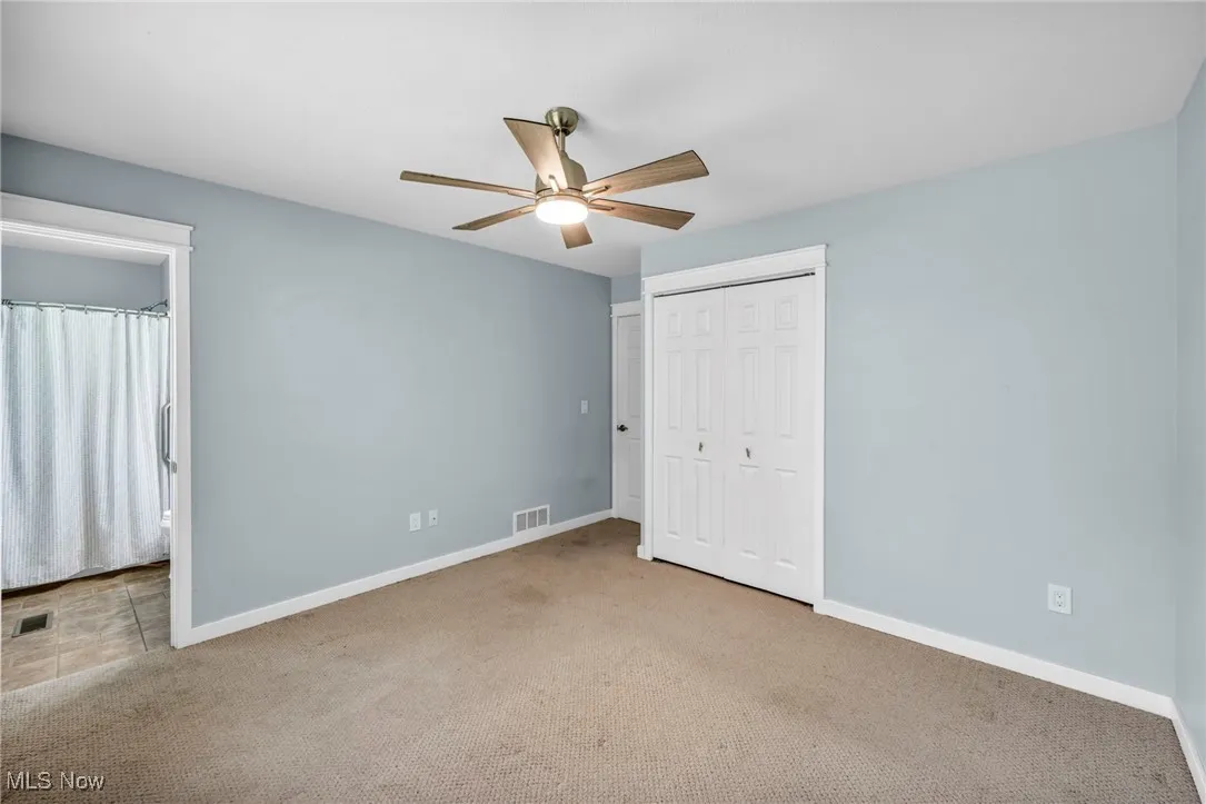 Unfurnished bedroom featuring carpet flooring, a closet, ceiling fan, and ensuite bathroom