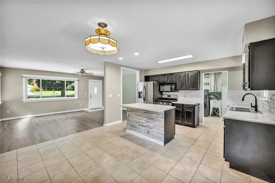 Kitchen featuring light tile patterned floors, tasteful backsplash, a center island, open floor plan, and stainless steel appliances