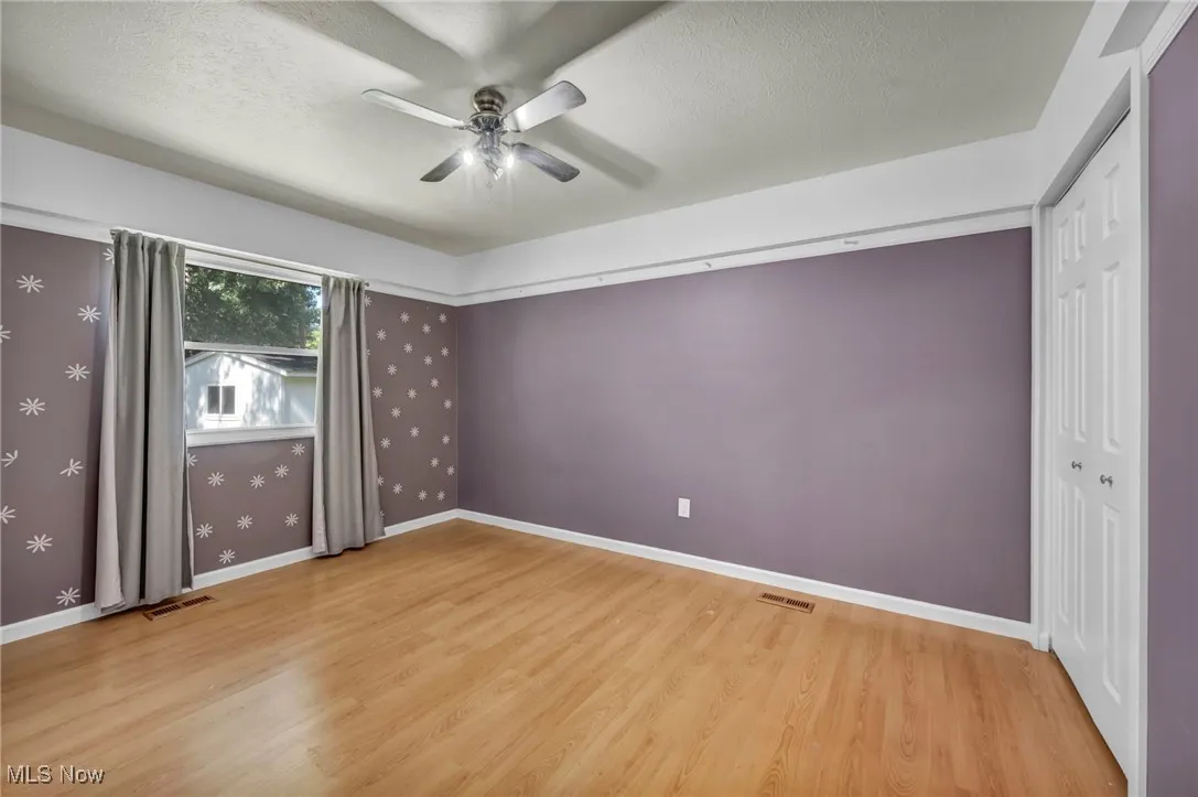 Unfurnished bedroom with light wood-style floors, a textured ceiling, a ceiling fan, and a closet