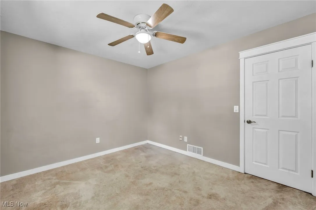 Unfurnished room featuring light colored carpet and ceiling fan