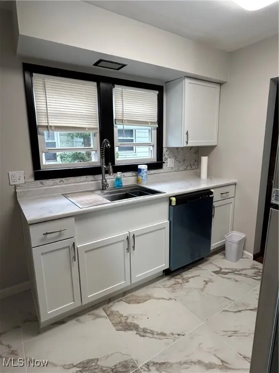 Kitchen with light marble finish floors, white cabinets, dishwashing machine, backsplash, and fridge