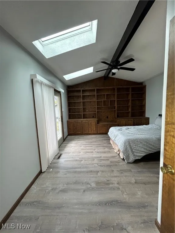 Bedroom with access to outside, light wood finished floors, a skylight, and ceiling fan