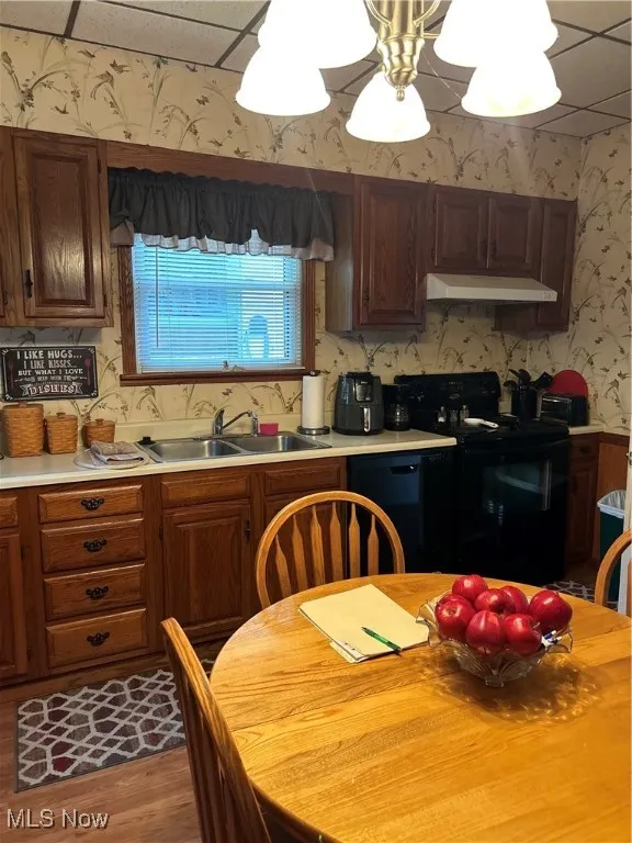 Kitchen featuring wallpapered walls, light countertops, stove, exhaust hood, and dishwasher