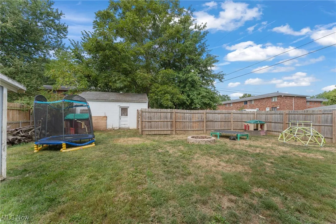Fenced backyard with a trampoline and an outdoor fire pit