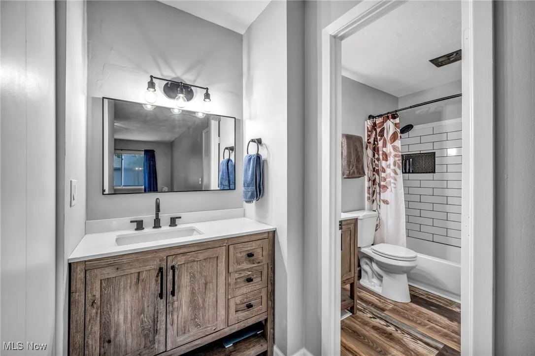 Full bathroom featuring vanity, dark wood finished floors, and shower / tub combo with curtain
