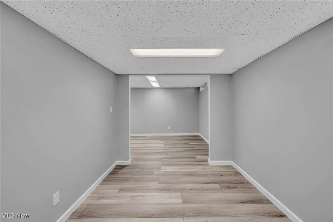 Finished below grade area with light wood-style floors and a paneled ceiling
