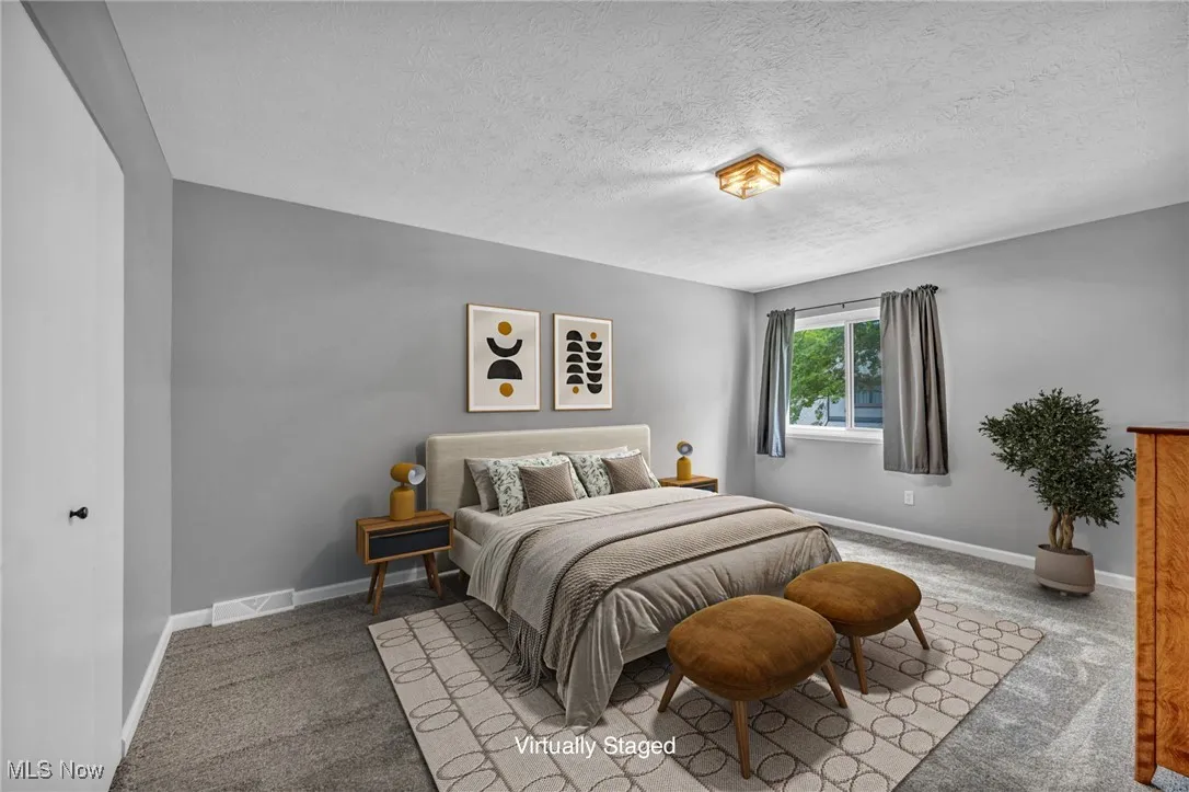 Carpeted bedroom featuring a textured ceiling and baseboards