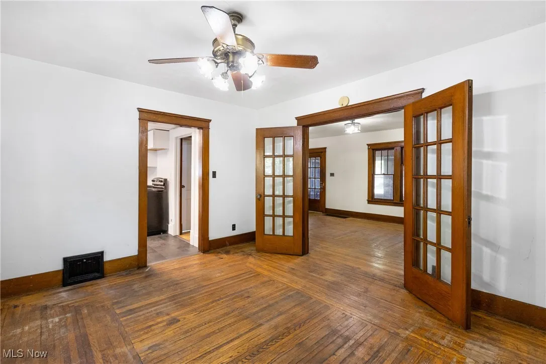 Unfurnished room featuring french doors, dark wood-type flooring, and a ceiling fan