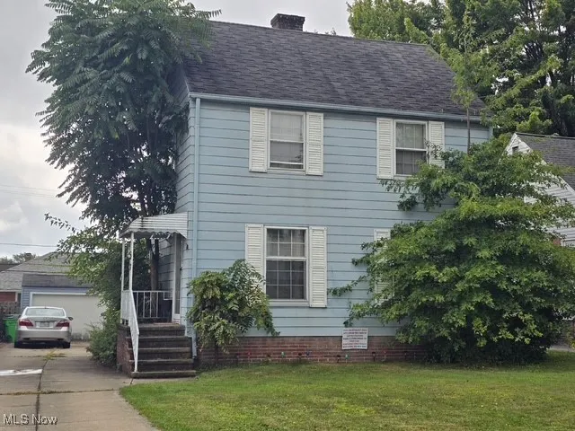 Colonial house with a chimney, a garage, and a front yard