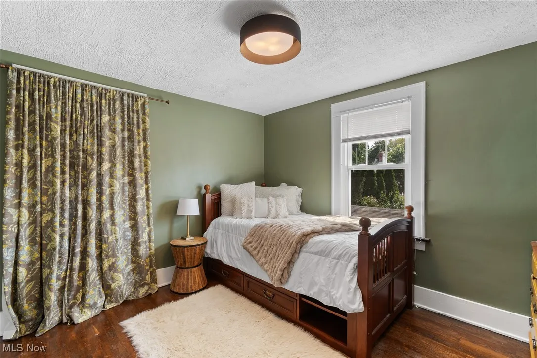 Bedroom with a textured ceiling and dark wood-type flooring