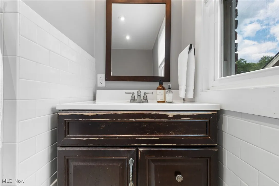 Bathroom with tile walls, vanity, and wainscoting