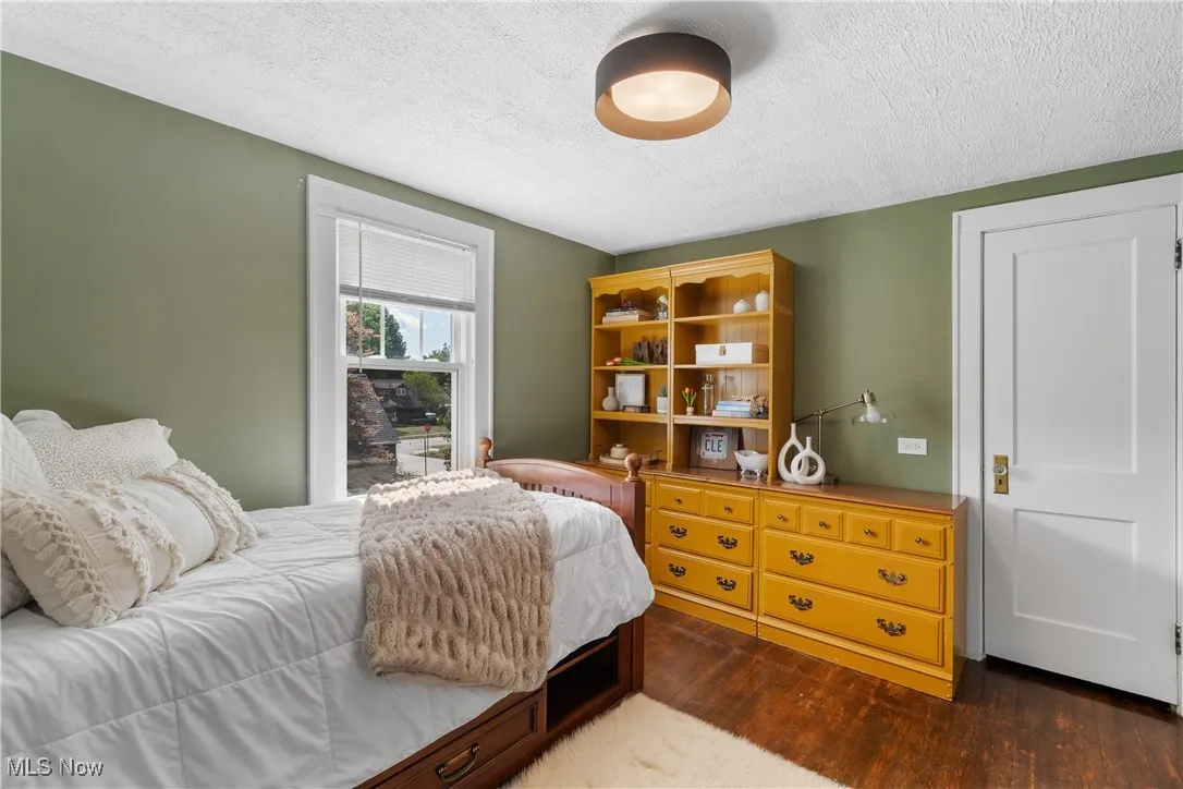 Bedroom with a textured ceiling and dark wood-style flooring