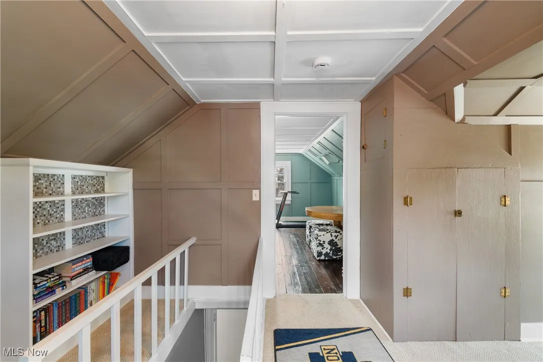 Hall featuring vaulted ceiling and a decorative wall