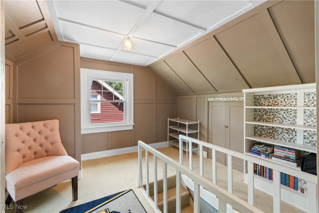 Bedroom with lofted ceiling, light carpet, and a decorative wall