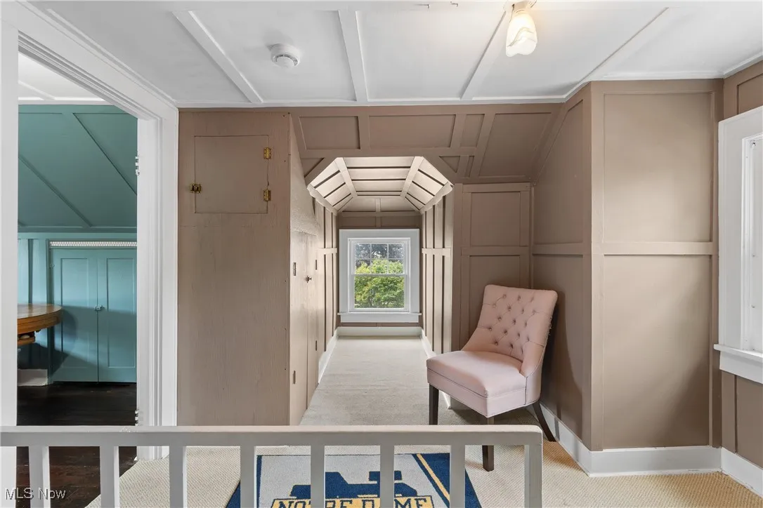 Bedroom with a decorative wall, light colored carpet, and lofted ceiling