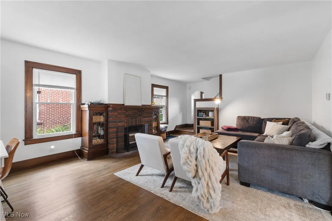 Living room featuring a brick fireplace, plenty of natural light, and wood finished floors