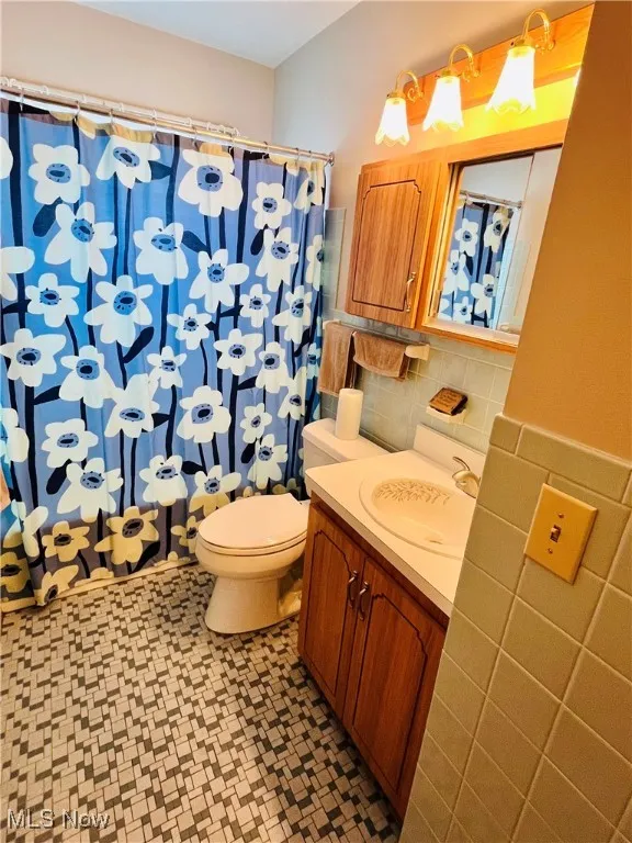 Full bath featuring tile walls, vanity, a shower with curtain, and decorative backsplash