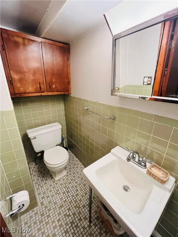 Bathroom with tile walls, tile patterned flooring, and wainscoting