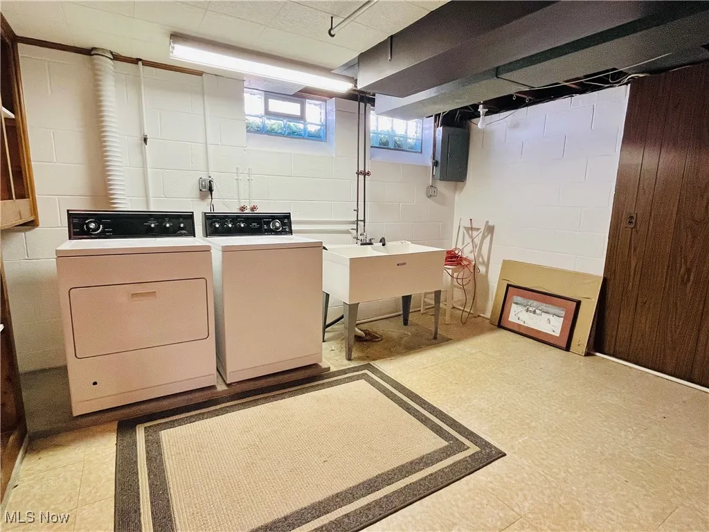 Laundry area featuring light floors, electric panel, and independent washer and dryer