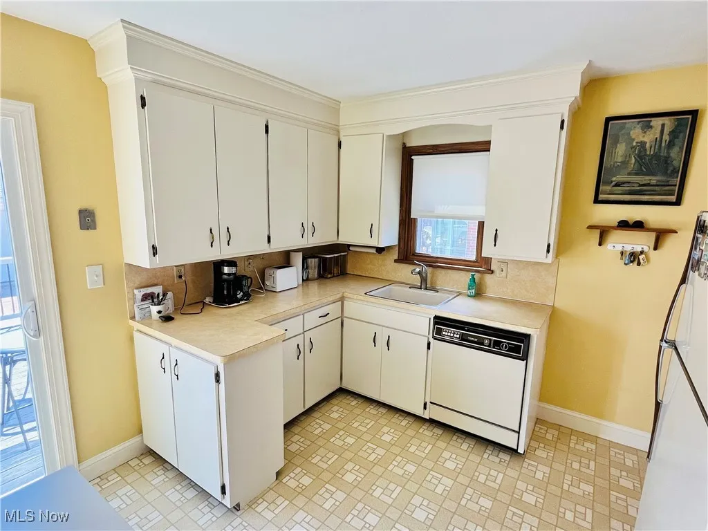 Kitchen featuring light countertops, white appliances, decorative backsplash, and white cabinetry