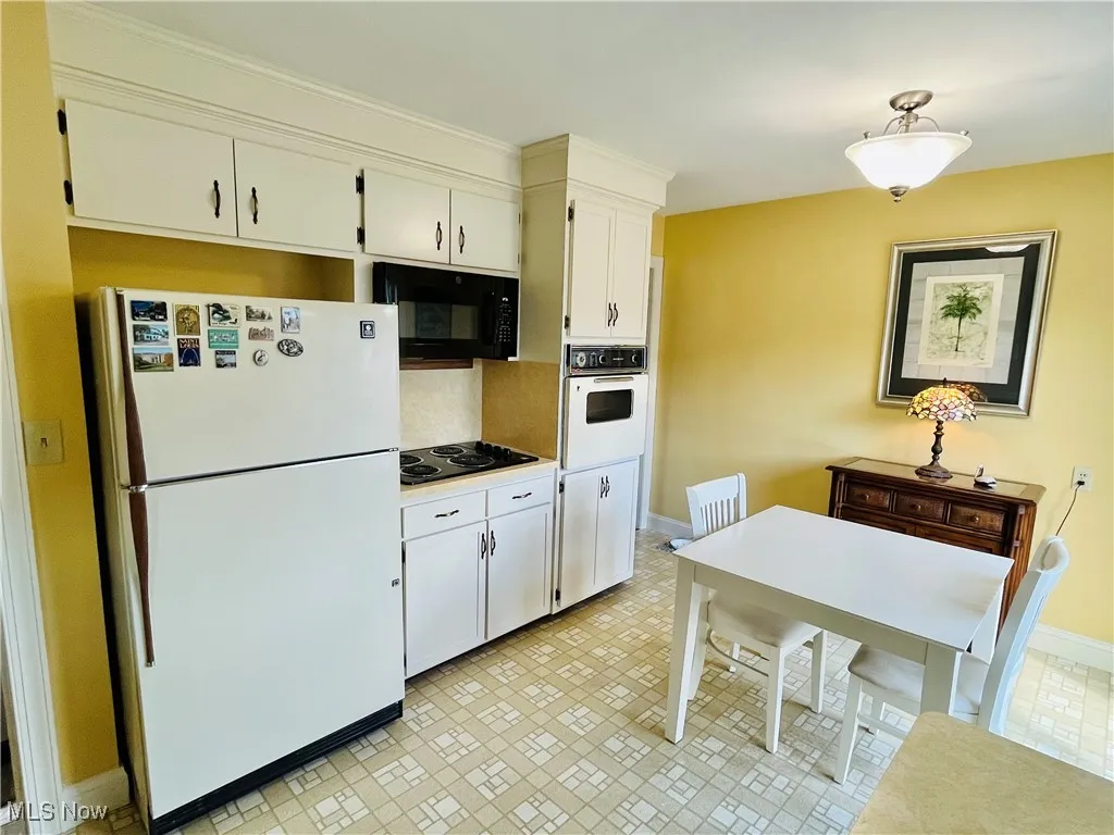 Kitchen with black appliances, white cabinetry, and light countertops